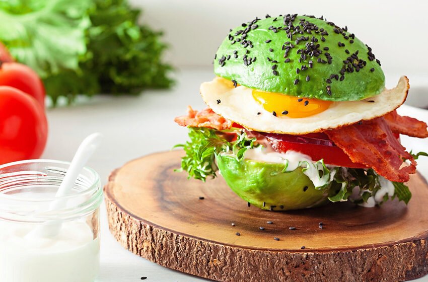 Lazy keto breakfast with eggs and bacon sandwiched inside an avocado